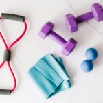 Colorful home workout equipment, including dumbbells and resistance bands, on a marble surface.